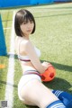 A woman sitting on a soccer field holding a soccer ball.