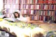 A woman laying on a bed in front of a book shelf.