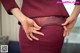 A woman in a maroon dress with her hands on her hips.