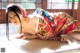 A woman in a kimono laying on a tatami mat.