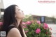 A woman with long black hair standing in front of pink flowers.