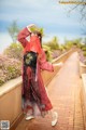 A woman in a red and black kimono standing on a brick walkway.