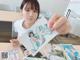 A woman sitting at a table holding up a picture of herself.