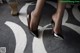 A close up of a woman's legs in high heels on a rug.