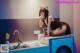 A woman sitting on top of a washing machine in a kitchen.