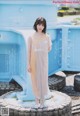 A woman standing in front of a blue trash can.