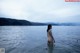 A naked woman standing in the middle of a body of water.